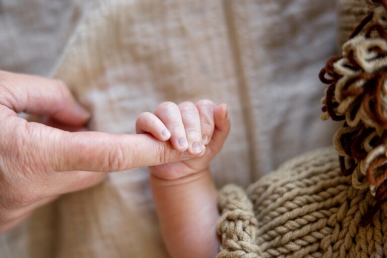 новородено държи пръст на родителя си